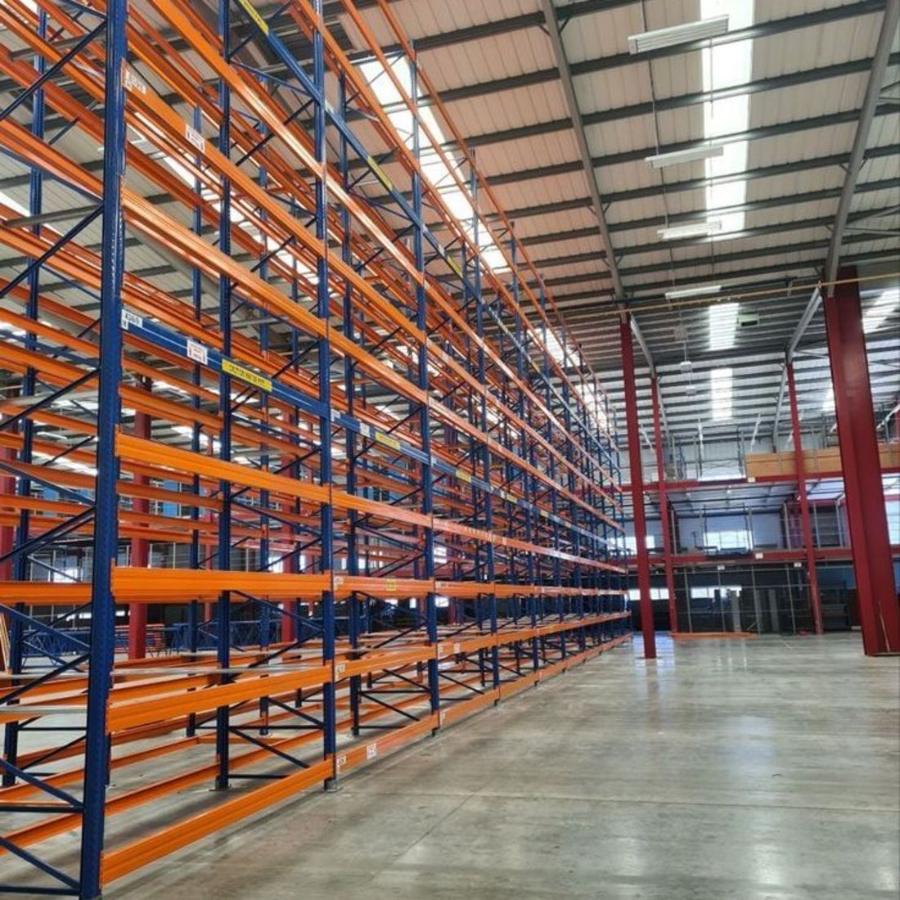 Fertig montierte Palettenregalanlage mit blauen Ständern und orangen Traversen in einer Logistikhalle